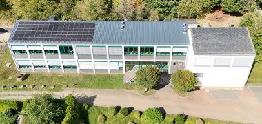 Foto links: Drohnenaufnahme der Grundschule Herresbach mit dem neuen Dach und der neuen Photovoltaikanlage
