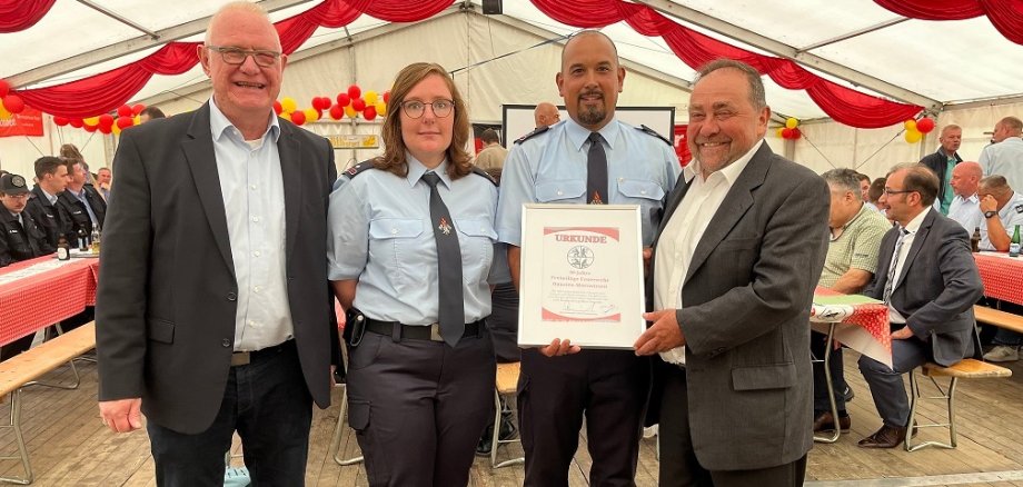 Das Bild zeigt Karsten Drescher, Vorsitzender des Fördervereins der FFW Hausten-Morswiesen, sowie der stv. Wehrführerin Carolin Scheffler bei der Verleihung der Urkunde von Bürgermeister Schomisch an Wehrführer Benedikt Bell 