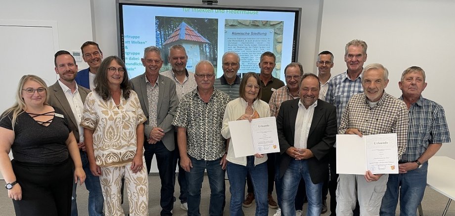 Das Bild zeigt Bürgermeister Alfred Schomisch (vordere Reihe, 2.v.r.) mit den Vertretern der Preisträger-Initiativen aus Nachtsheim, Maria-Theresia Gerharz (vordere Reihe, 3.v.r.) und H.-Josef Gerharz (vordere Reihe, 1.v.r.) sowie den weiteren Anwesenden bei der feierlichen Verleihung des Umweltschutzpreises 2024 der Verbandsgemeinde Vordereifel